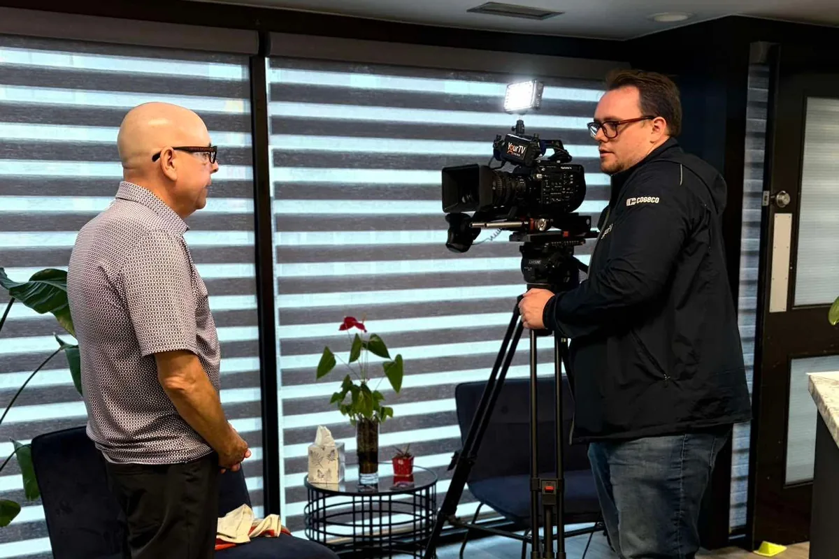 Paul Meyers standing across from a Cogeco camera operator setting up a tripod-mounted broadcast camera at the Chamber office