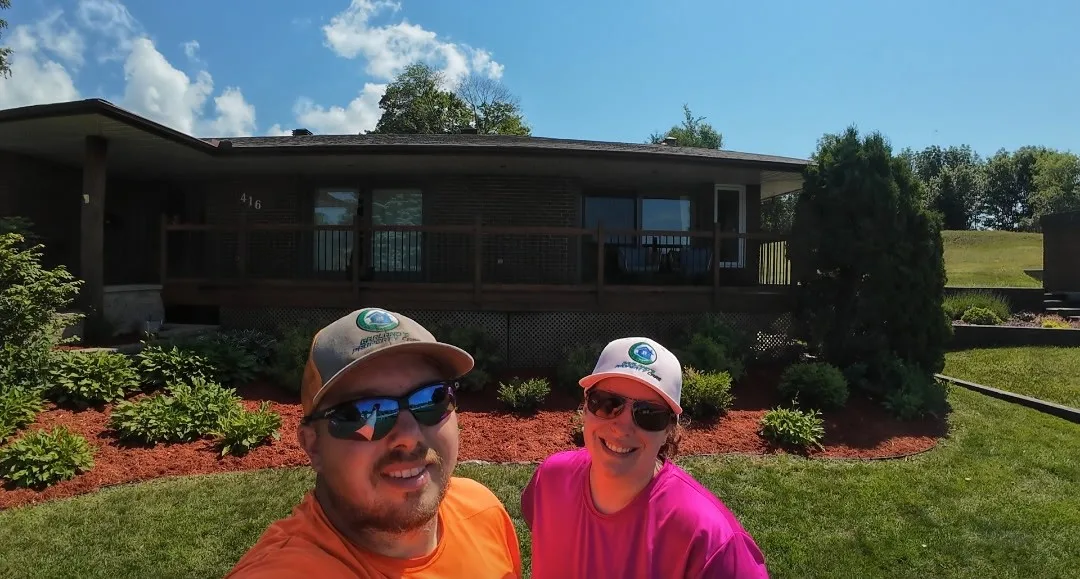 Lucas and Sarah of Garland's Property Care in front of a freshly mulched and planted garden bed on Airport Hill in North Bay